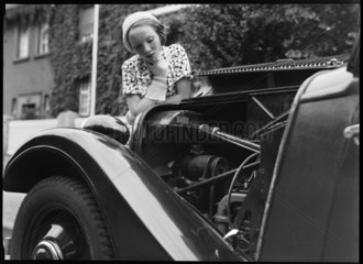 A woman looks at the engine of an Adler motor car  Germany  c 1934.