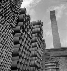 Hundreds of finished steel tubes stacked in yard by chimney  1948.