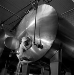 Man washes out large aluminium tank used in chocolate production  Ilford.