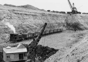 Train of iron ore tipplers in quarry with 0-4-0T and walking drag lines.