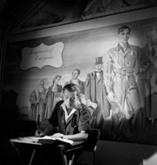 An engineering apprentice studies in front of pageant mural 1950.