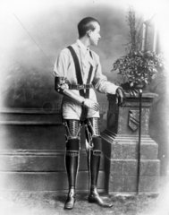 Young man wearing artificial legs and an artificial arm  1890-1910.