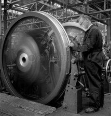 A fitter guages new locomotive wheels as they run at speed in a test bay  1951.
