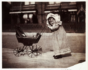 Child pushing a toy pram  c 1895.