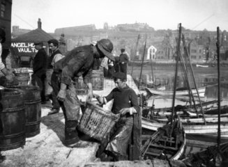 Fishermen unloading baskets of fish  Whitby  North Yorkshire  c 1900s.