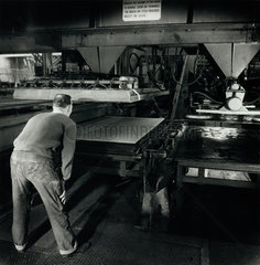 Operator with press used to laminate asbestos sheets for display  1961.