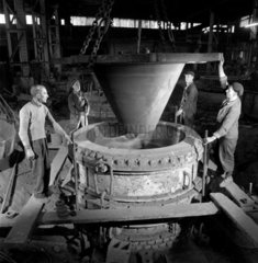 At Widnes Foundry  men insert a large core to shape a prepared mould.