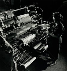 A female worker winds rolls of asbestos based string on machine  1961.