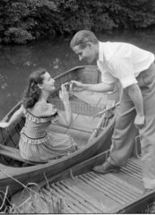 Man lighting a cigarette for a woman in a boat  1950.