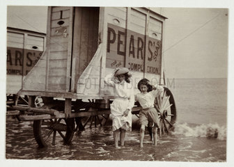 Girls paddling beside bathing machines  c 1900.
