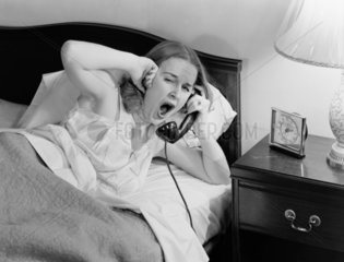 Yawning woman answering a telephone  c 1950.