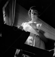 Female worker with nylon warp straightens twisted ends on the loom.