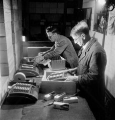 Two men packing Plus and Sumlock calculators  1949.