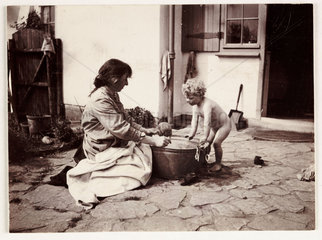 Woman washing a baby in a tin bath  c 1900.