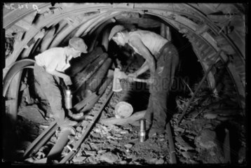 Underground repairman and child cutting timber in a mine  1931.