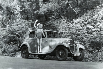 Girl in a swimming costume with a Riley car  c 1930s.