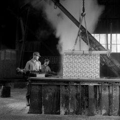 Two men lift steel flooring from galvanising bath  Charlton  1959 .