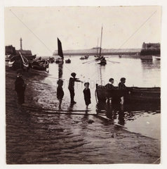 A group of boys playing by a boat  c 1905.