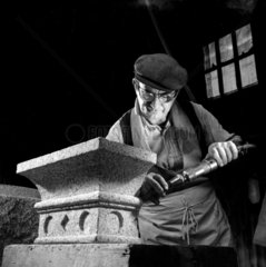 A Peryn stone worker moulds an oranamental granite cornice by chisel.