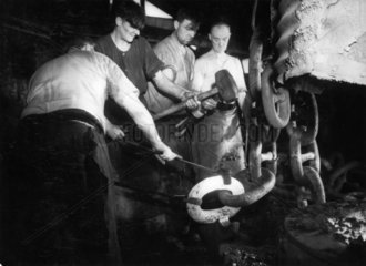 Men forging a large chain  mid 20th century.