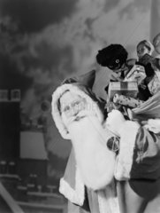 Father Christmas carrying a sack of presents  1950.