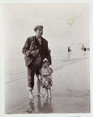 Man and small child paddling in the sea  c 1910.