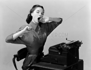 Woman yawning at a typwriter  1950.