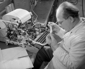 Production of Envoy telex machine: an engineer inspects tape  1968.