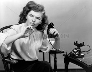 Woman using the telephone asking for quiet  c 1950.