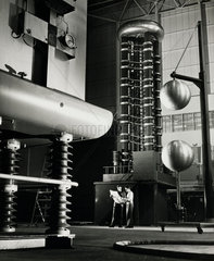 Two engineers against huge tubes and spheres  high voltage test hall  AEI.