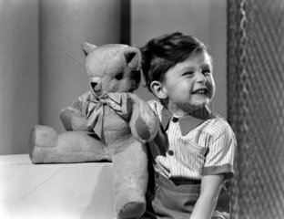 Laughing little boy with a teddy bear  c 1950.