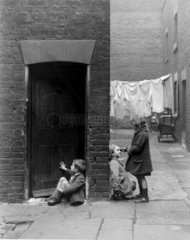 Children playing outside their slum home in Southwark  16 December 1932.