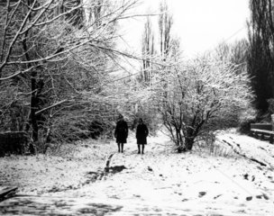 Two schoolboys strolling in the snow in a p