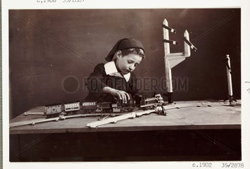 Boy playing with a toy train  c 1900.
