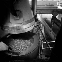 Electrode production: man with large vat of material in 40 foot extrusion press.