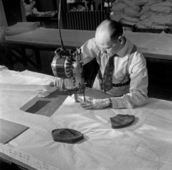 A worker uses a motor to cut sheets of synthetic material  Tottenham  1958.