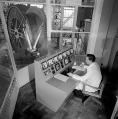 An operator at a high voltage control console looks out on to the test section.