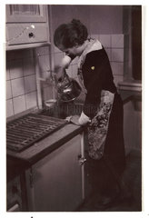 Woman at a kitchen sink  c 1935.