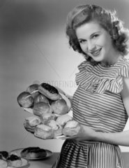 Woman holding plates of cakes  c 1950.