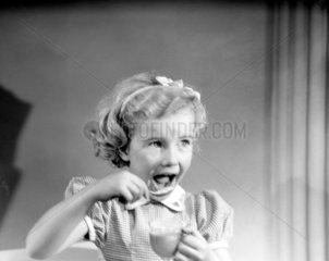 Little girl eating dessert  c 1950.