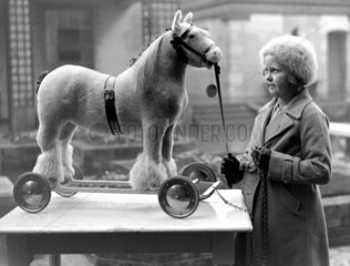 Young girl looking at a toy cart horse on w