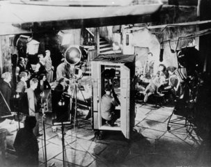 Early sound studio with cine camera encased in sound-proof booth  c 1920.