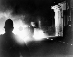 Police officers watching a car burning  London  April 1981.