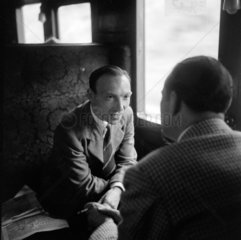 Colin Wills of the BBC talking with a man during a train journey  1950.
