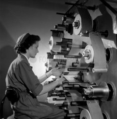 A female worker at wax roll winding machine used in capacitors  1956.