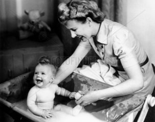 Woman bathing a baby  1940s.