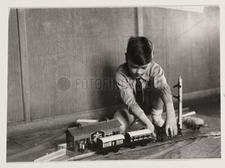 Boy playing with a train set  c 1930.