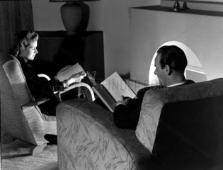 Man and woman reading by a fireside  1950.
