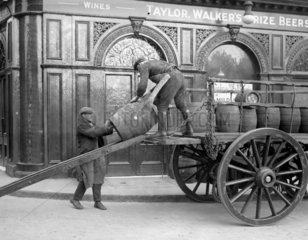 Draymen lowering barrels of beer into vault