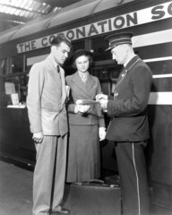 Conductor checking the booking of a young couple  1937.
